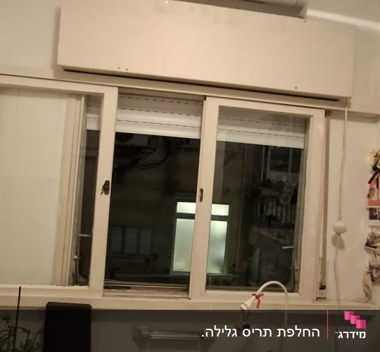 חלון עם תריסים ומזגן מעל שולחן